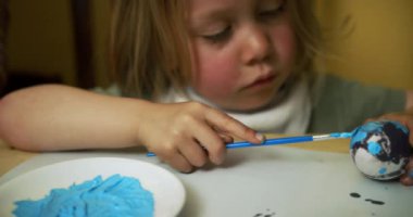 Anne ve küçük oğlu paskalya yumurtası boyuyor.