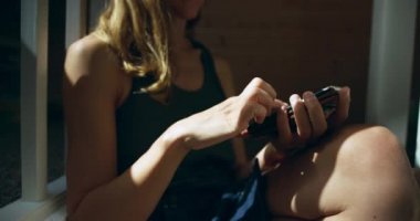 Merdivenlerde oturan ve smartphone kullanarak genç kadın