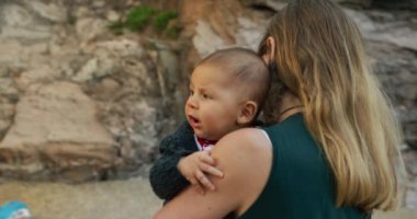 Sevimli küçük çocuk deniz kenarında annesiyle vakit geçiriyor.