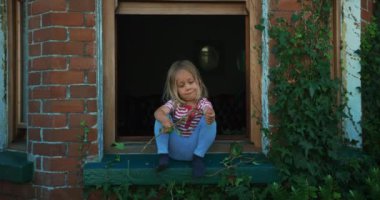 Küçük çocuk pencerenin kenarında oturuyor.