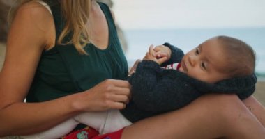 Sevimli küçük çocuk deniz kenarında annesiyle vakit geçiriyor.