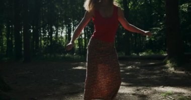 Güneşli ormanda dönen güzel bir kadın