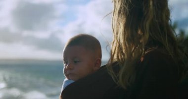 Anne oğlunu deniz kenarında tutuyor.