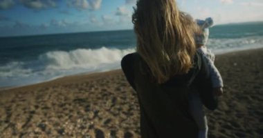 Sevimli küçük çocuk deniz kenarında annesiyle oynuyor.