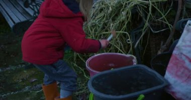 Küçük çocuk dışarıda çekiçle buz kırıyor.