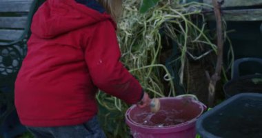 Küçük çocuk dışarıda çekiçle buz kırıyor.