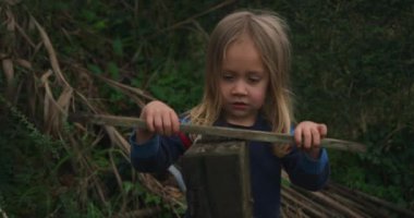 Ormanda tahta bir sopayla oynayan tatlı bir çocuk.