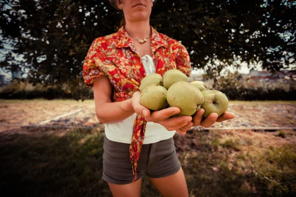 Young woman standing by tree with apples — Stock Photo, Image