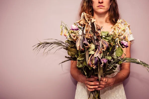 Young woman holding bouquet of dead flowers — Stock Photo, Image