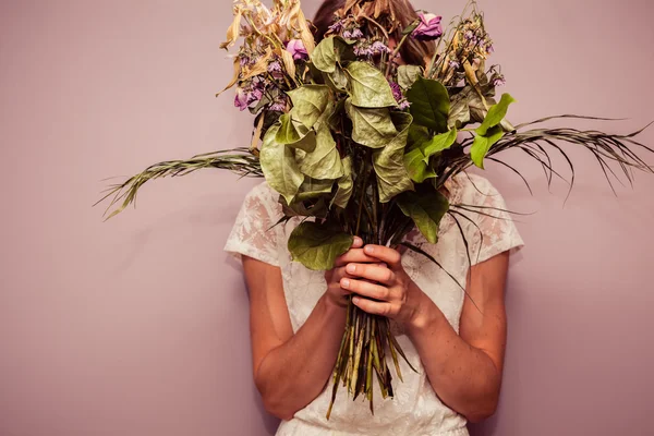 Young woman holding bouquet of dead flowers — Stock Photo, Image