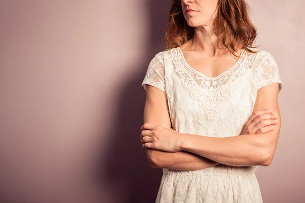 Молодая женщина в белом платье стоит у фиолетовой стены — стоковое фото