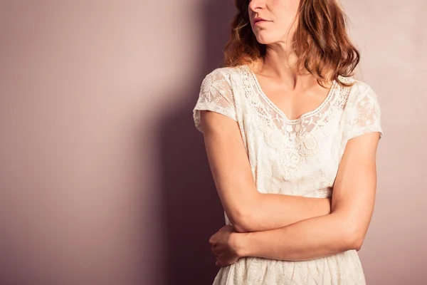 Young woman in white dress standing by purple wall — Stock Photo, Image