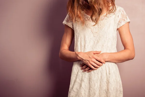 Mide ağrıları ile beyaz elbiseli genç kadın — Stok fotoğraf