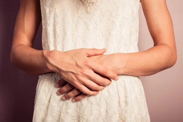 Młoda kobieta w białej sukni z bóle brzucha — Zdjęcie stockowe
