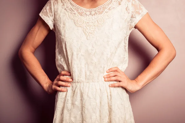 Young woman in white dress standing by purple wall — Stock Photo, Image