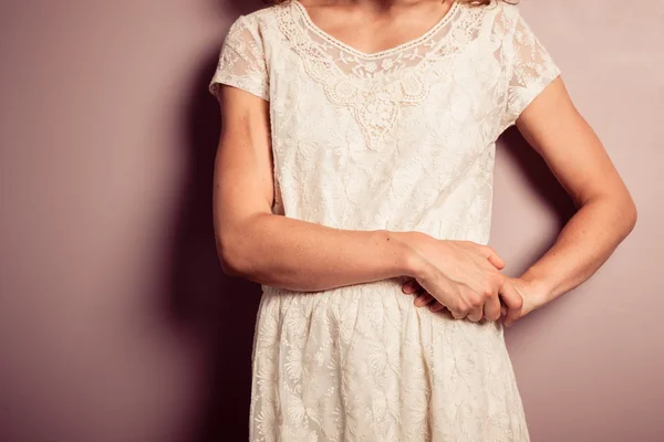 Young woman in white dress standing by purple wall — Stock Photo, Image