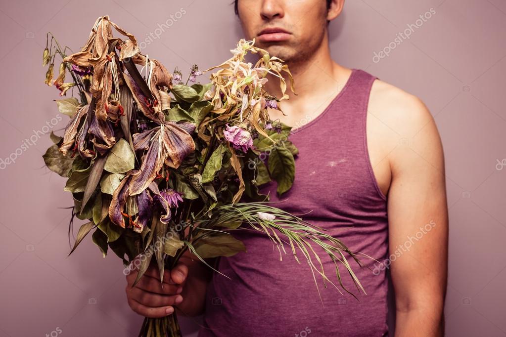 Young man holding bouquet of dead flowers — Stock Photo © lofilolo 51957271