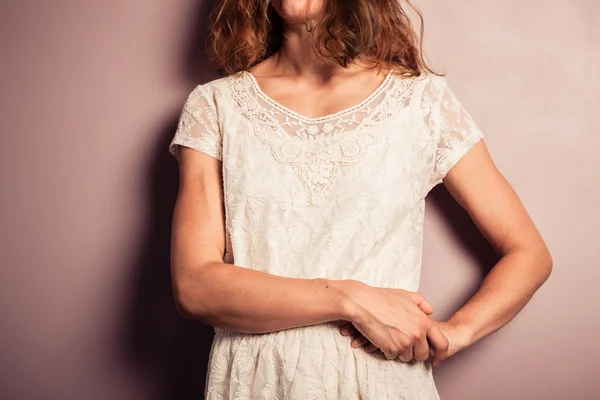 Ung kvinna i vit klänning stående av lila vägg — Stockfoto