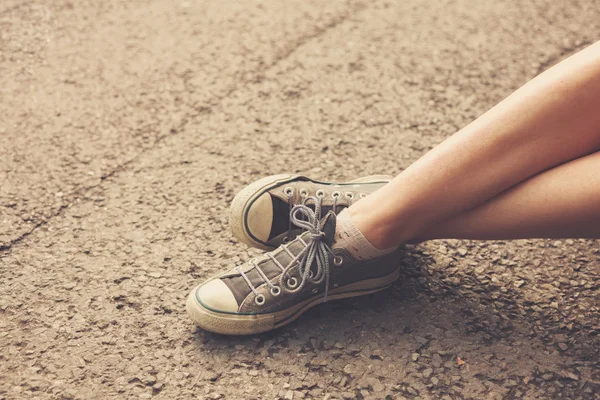 The feet of a young woman sitting in the street — Stock Photo, Image