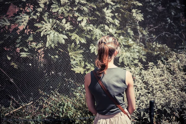 Woman standing by a fence — Stock Photo, Image