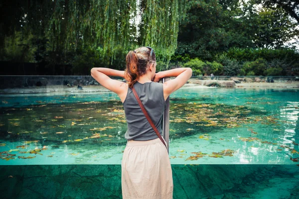 Jonge vrouw permanent door een grote tank water — Stockfoto