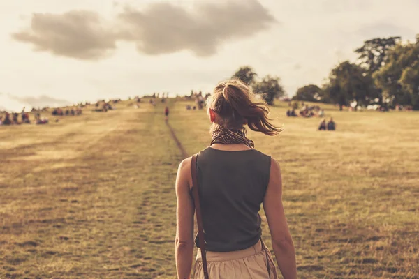 Jonge vrouw wandelen in het park bij zonsondergang — Stockfoto