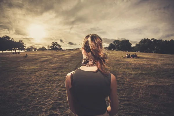 Ung kvinna promenader i parken vid solnedgången — Stockfoto