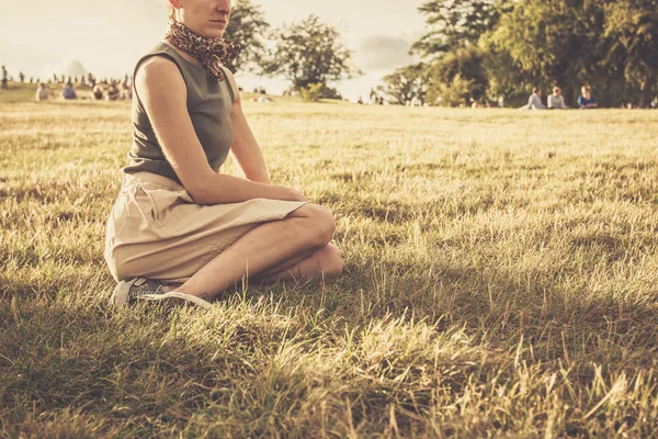 Giovane donna seduta su una collina al tramonto — Foto Stock