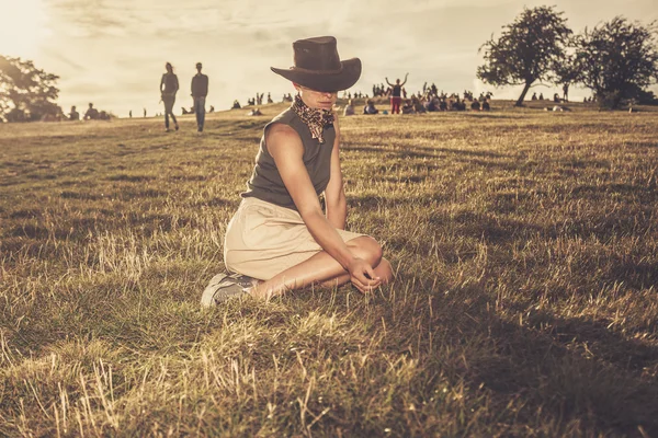 Young woman sitting on a hill at sunset — Stock Photo, Image