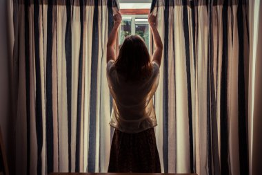 güneş doğarken perdeleri açmayı genç bir kadın