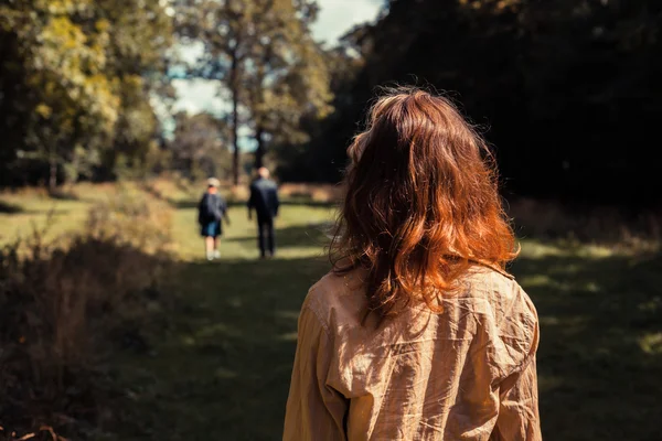 Młoda kobieta w lesie, patrząc na ludzi przed jej — Zdjęcie stockowe