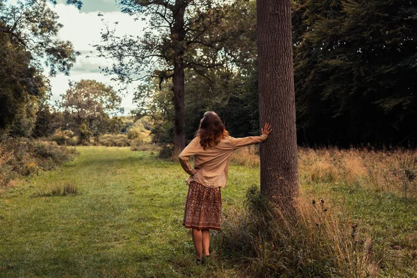 Joven mujer lamiendo contra un árbol en el bosque —  Fotos de Stock