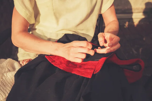 Young woman sewing outside — Stock Photo, Image