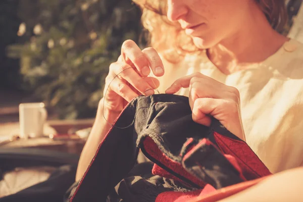 Mujer joven cosiendo fuera — Foto de Stock