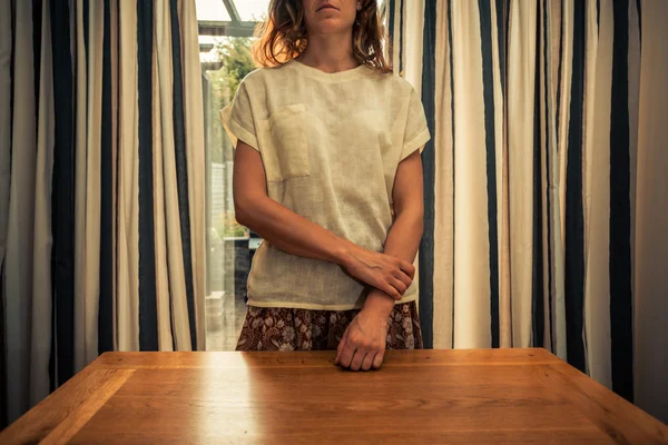 Młoda kobieta stojąc przez zasłony francuskie drzwi — Zdjęcie stockowe