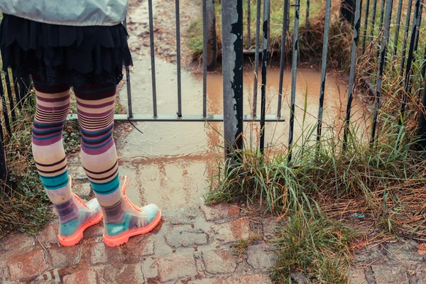 Young woman in boots standing by puddle — Stock Photo, Image