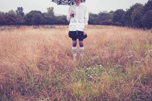 Jeune femme avec parapluie debout dans le champ — Photo