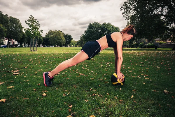 Young woman exercising with medicine ball in park — Stock Photo, Image