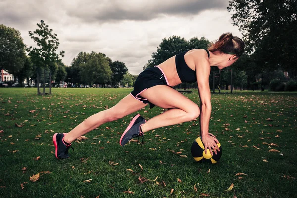 Young woman exercising with medicine ball in park — Stock Photo, Image