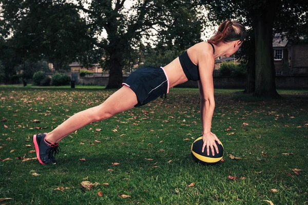 Young woman exercising with medicine ball in park — Stock Photo, Image