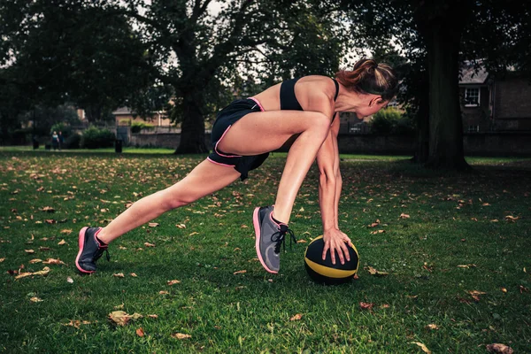 Mujer joven haciendo ejercicio con balón de medicina en el parque —  Fotos de Stock