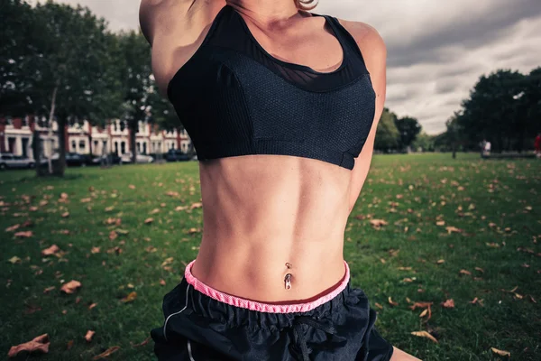 Fit jonge vrouw stretching in het park — Stockfoto
