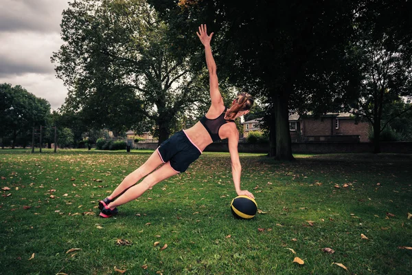 Mujer joven haciendo ejercicio con balón de medicina en el parque —  Fotos de Stock