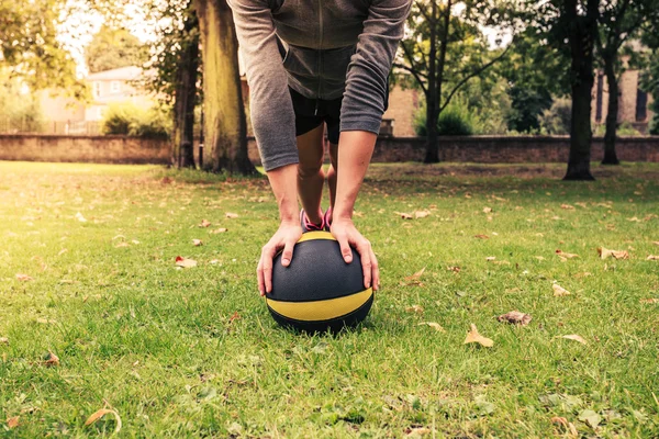 Young woman exercising with medicine ball in park