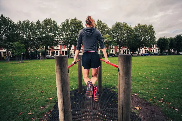 Young woman doing dips in the park — Stock Photo, Image