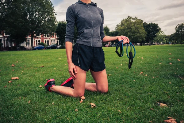 Vrouw uit te werken met weerstand band in het park — Stockfoto