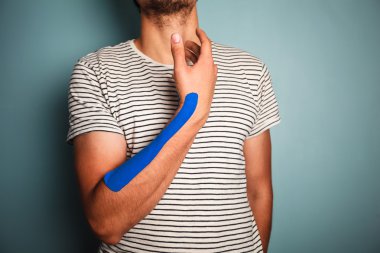 Young man with kinesio tape on his arm clipart