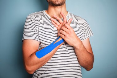 Young man with kinesio tape on his arm clipart