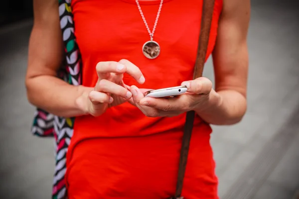 Junge Frau steht mit ihrem Handy auf der Straße — Stockfoto