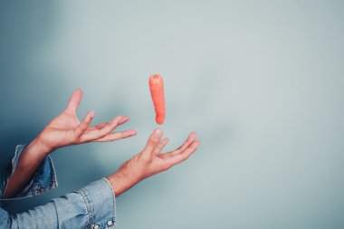genç adam havaya kaldırmak bir carrot yapma